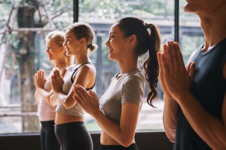Group of young people practicing yoga In the prayer position at gym, Concept of relaxation and meditationの写真素材