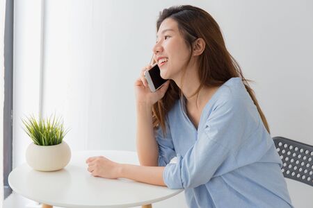 Beautiful of young Asian woman using smartphone while sitting at homeの写真素材