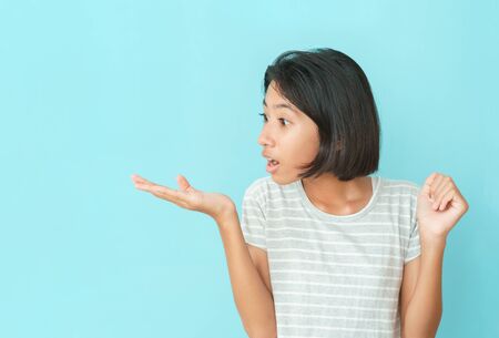 Asian girl expression excited on face on the background blue isolated, Asia child standing is wow mouth open with open palm at copy space for your text or advertisementの写真素材