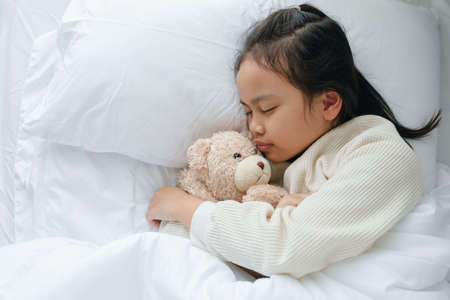 Asian little girl sleeping and hug teddy bear in the bedroom	

の写真素材