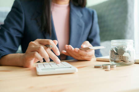 Hand of businesswoman doing calculating and holding banknote at the table, finance, and saving money for the future concept.の写真素材