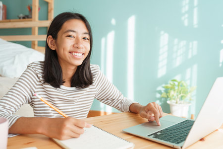 Asian girl learning online via the internet tutor on a laptop computer, Asia child is studying while...