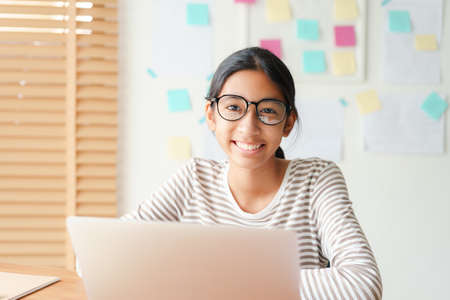 Happy Asian little girl smile on the face, Asia child wear glasses while sitting in interior home. Portrait of a kid looking to camera.の写真素材