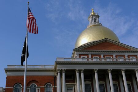 Looking up at the Massachusetts State House a deep blue sky is in the background and both the american flag and the pow/mia flags are in the foreの写真素材