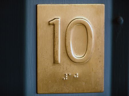 a golden colored number ten with ten written in braille beneath itの写真素材