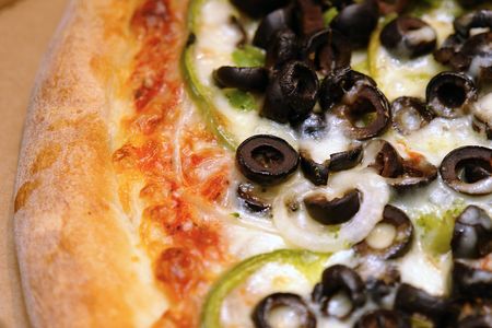 close up of freshly baked pizza with olives, onions, broccoli, peppersの写真素材