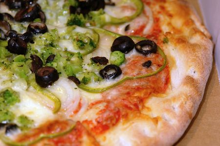 close up of freshly baked pizza with olives, onions, broccoli, peppersの写真素材