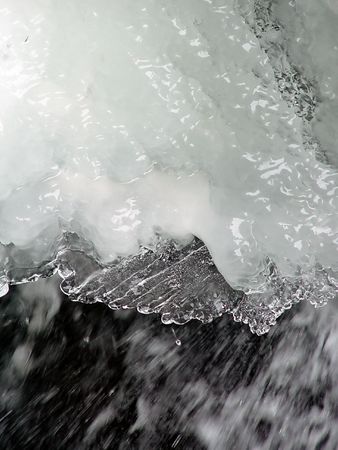 large section of snow and ice above  flowing waterの写真素材