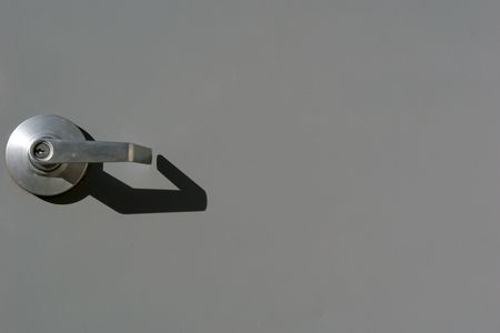 a steel grey door with the handle on the left with strong shadow from the morning sunの写真素材