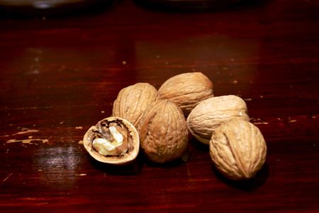 collection of walnuts on red wood kitchen counter, one has been opened