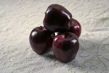 four red delicious apples on white lace table cloth, lit by the natural light of the morning sun, old fashioned down home lookの写真素材