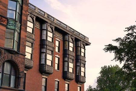 Upper floors of old brownstone apartment building in boston, massachusetts on a spring afternoon. showing ornate glass work, iron work and brick workの写真素材