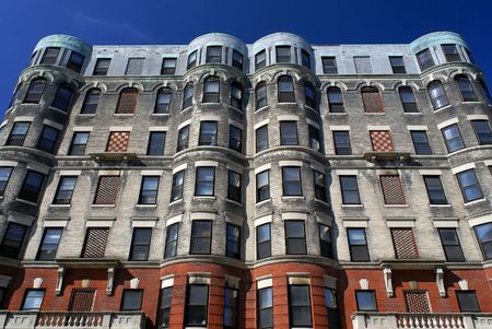 subtle yet ornate apartment house in downtown cambridge massachusetts with checker board designs and round corners against a deep blue skyの写真素材