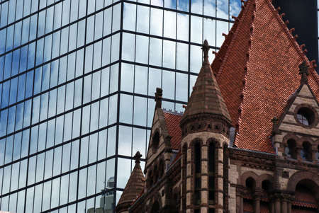 the sky is vividly reflected on large glass mirrored skyscraper building in boston's back bay behind trinity church in copley squareの写真素材