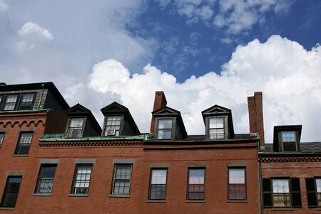 row houses along charles street in boston with cumulous clouds in the background