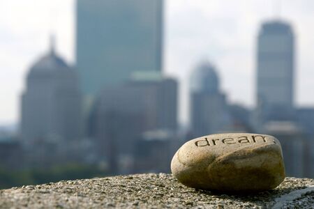 dream rock sits on cement ledge with the boston skyline in the background,representing dreams of...