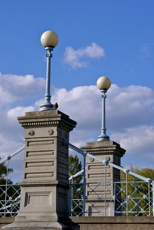 a pigeon sits on one of the cement pillars holding up the bridge in boston's public gardens at the base of the light poleの写真素材