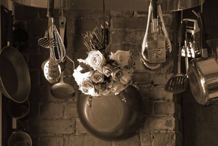 sepia toned image of country kitchen with roses hanging from the pot rack drying                  の写真素材