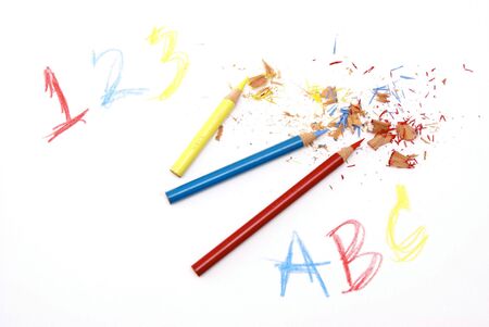 bright colorful image of freshly sharpened colored pencils, red, blue and yellow, with shavings on white drawing paper with numbers and lettersの写真素材