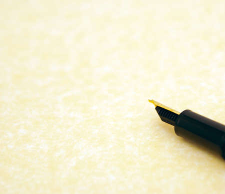 beautiful gold tipped fountain pen resting on the edge of a sheet of parchment writing paper, with lots of open spaceの写真素材