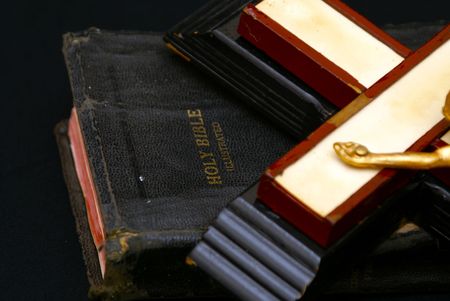 close up image of an old crucifix laying on top of an ancient leatherbound bible