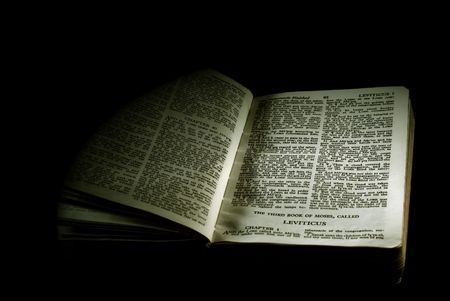 detail of an old antique holy bible against a black background open to the third book of moses called leviticus finished in sepiaの写真素材