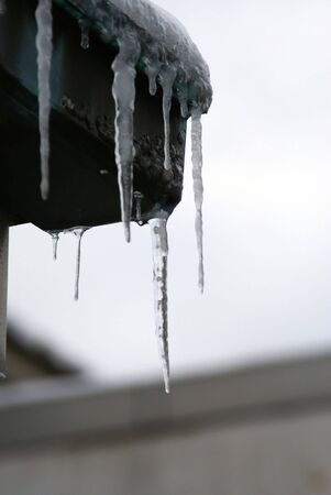 detail of icicles on gutter of roof on a snowy day