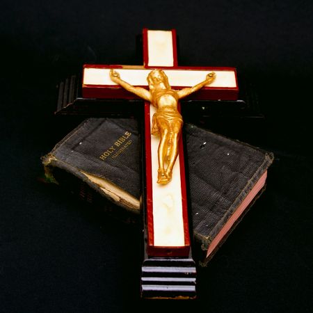full color image of an old crucifix laying on top of an ancient leatherbound bibleの写真素材