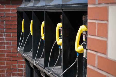 bank of five public telephones surrounded by brickの写真素材
