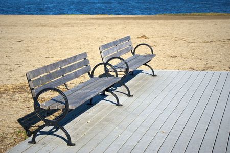 two empty park benches on an abandoned beach on deckの写真素材