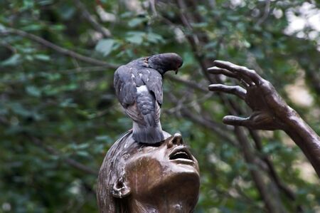 public statue of woman with open mouth in boston massachusetts with two pigeons looking like she is trying to remove bird from faceの写真素材
