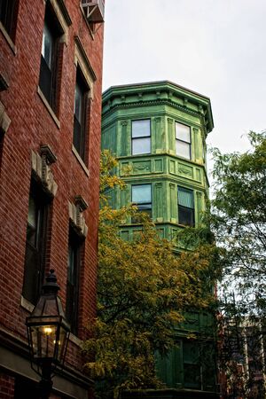 old oxidized building rises up over trees in the fall on beacon hill in boston massachusettsの写真素材