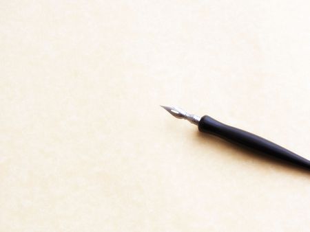 old fashioned ink dip pen for writing or drawing on parchment paper background