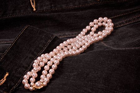 pearl necklace laying on black denim jacket の写真素材