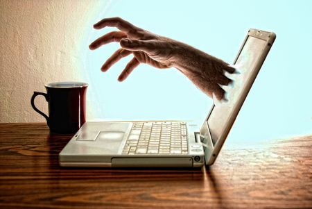 modern white norebook laptop computer sitting on desk with red coffee cup  with hand reaching out of screen for the coffeeの写真素材