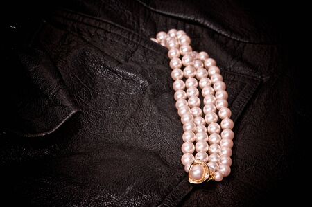 four strands of pearls coming out of pocket of black leather jacket with gold and diamondsの写真素材