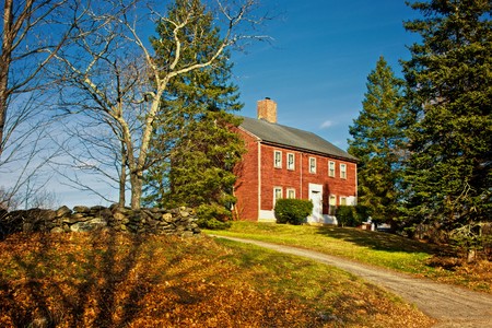 old red colonial house up on hill in nottingham new hampshire on a fall afternoonの写真素材