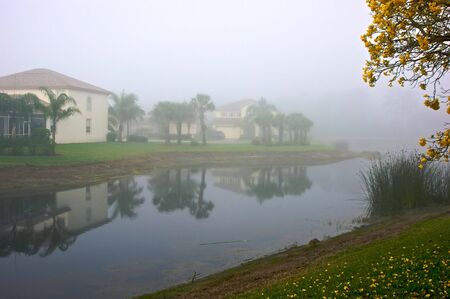foggy morning in florida showing lake front homes reflected in waterの写真素材