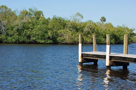 pier over water with trees in background with reflections in the rippling waterの写真素材