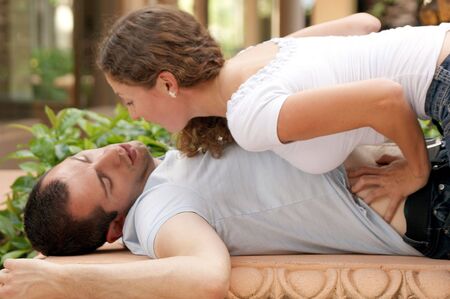 beautiful woman leaning in close  on top of man who is laying on his  back with his arms up, she is...