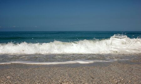 A low angle view of the ocean tide coming in, showing the wet beach, the undertow and wave crashing...