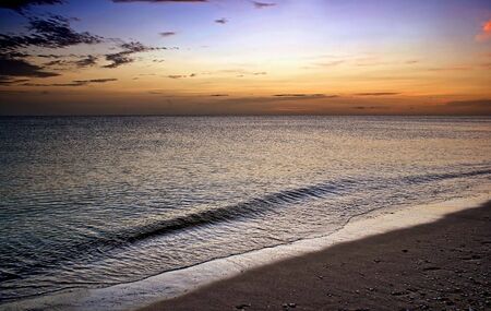 waves gently rolling to shore under a vivid sunsetの写真素材
