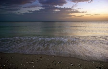 low angle view of tide water being drawn back into the sea at duskの写真素材