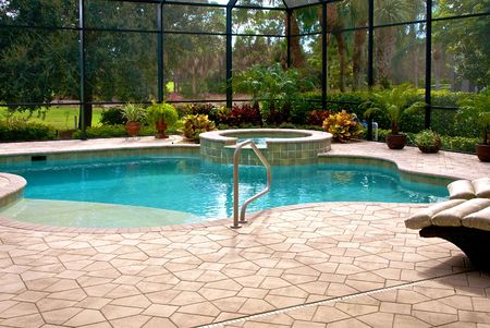 Large swimming pool surrounded by plants and screened in lanai.の写真素材