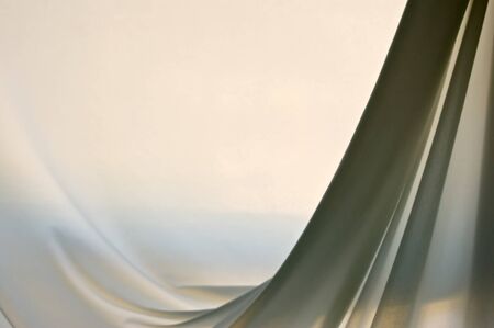 a soft nylon light colored cloth is gently draped creating folds in this back lit image.