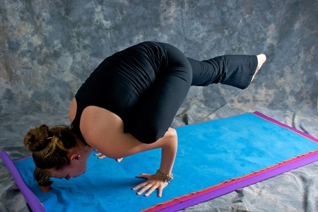 A brown haired caucasian woman is doing yoga exercise, Galavasana posture or sage pose, and...