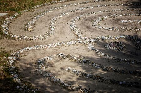 Looking down on a stone and sea shell maze or labyrinth with dirt pathsの写真素材