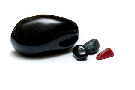 A collection of four smooth dark rocks used for massage over white. One large rock and three small.の写真素材