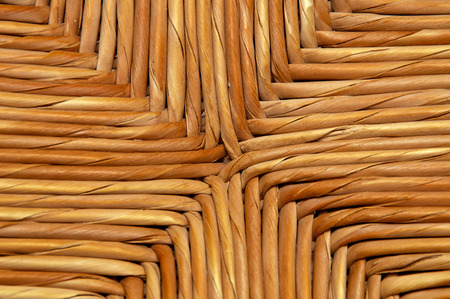 A woven wicker surface made up of strands of reeds woven together close up.