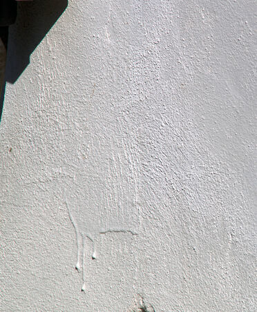 A white stucco wall with drips in the sunshine.の写真素材
